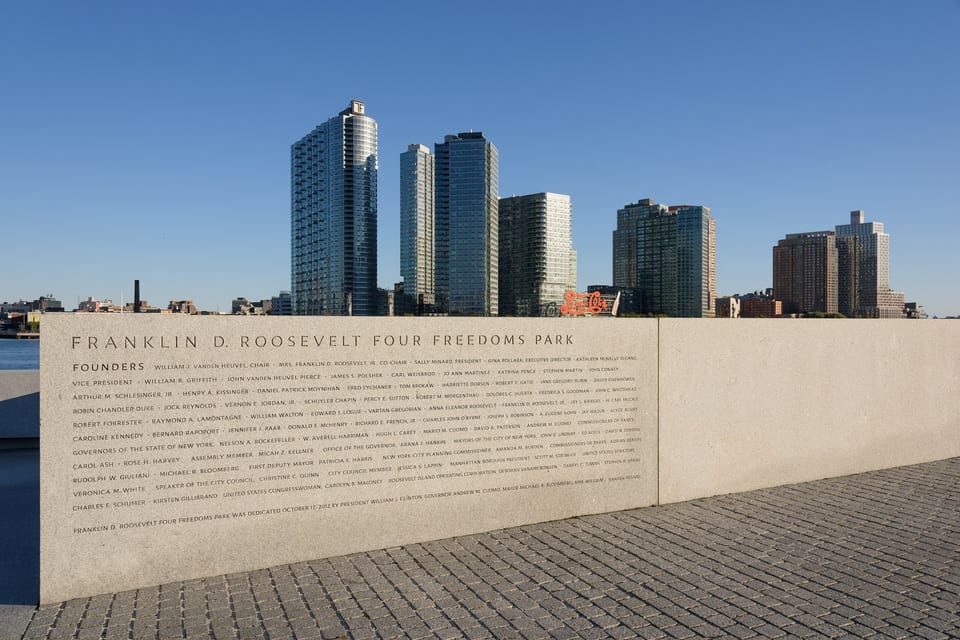 Granitowa tablica parku Four Freedoms na Roosevelt Island, w tle panorama Long Island City.